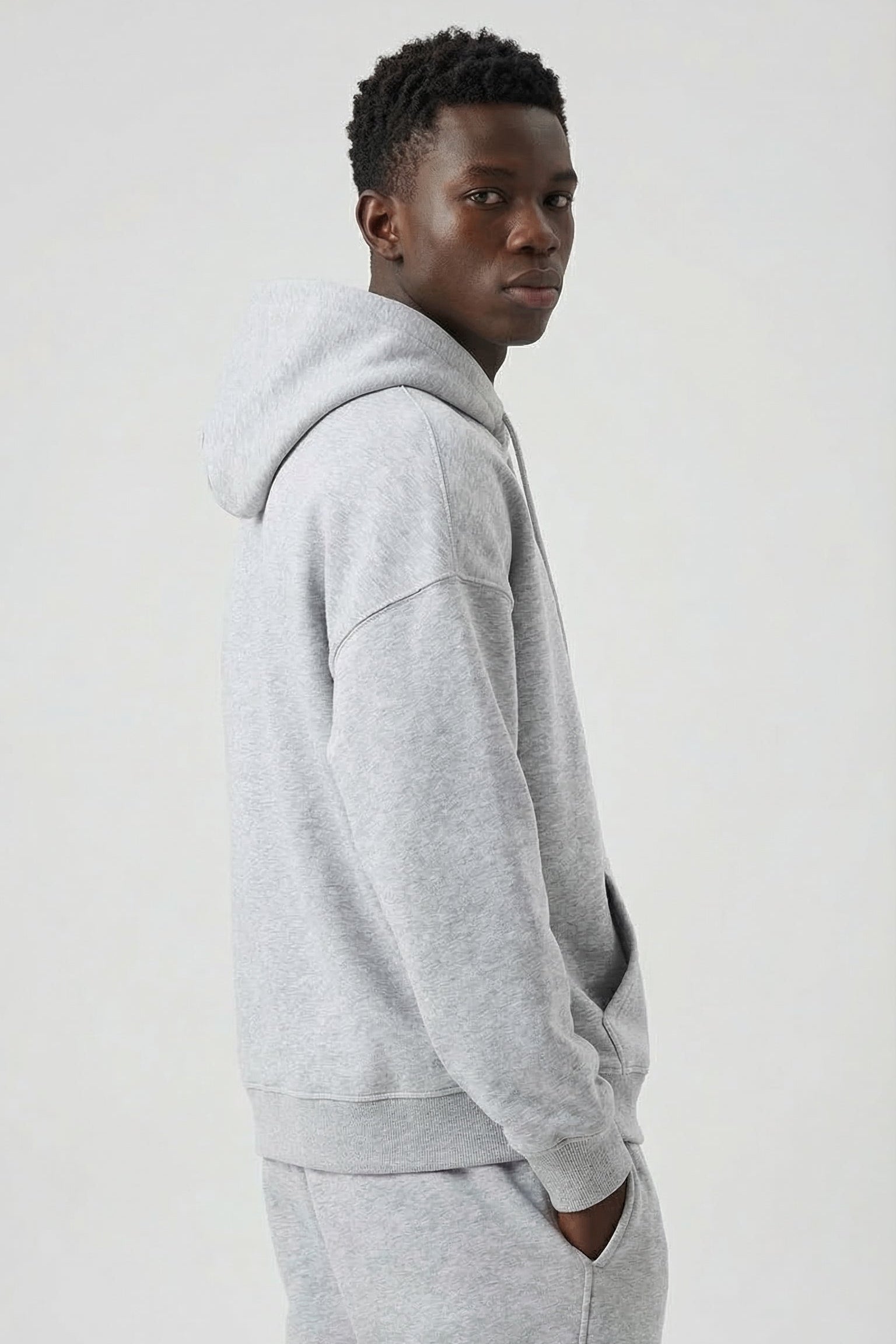 Person wearing a gray hoodie and pants on a white background