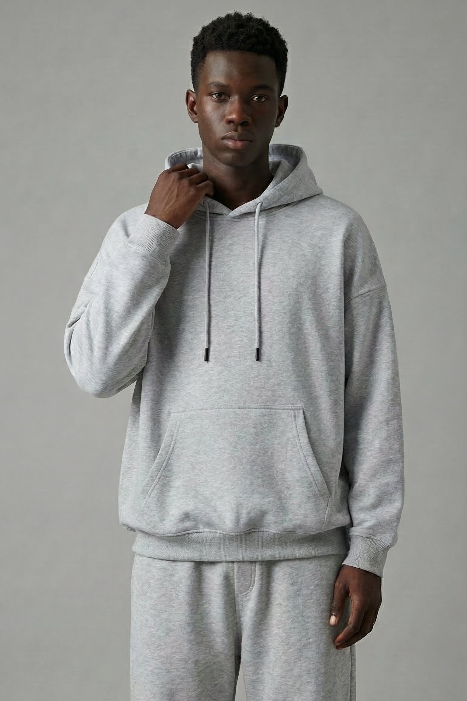 Person wearing a gray hoodie and pants on a plain background