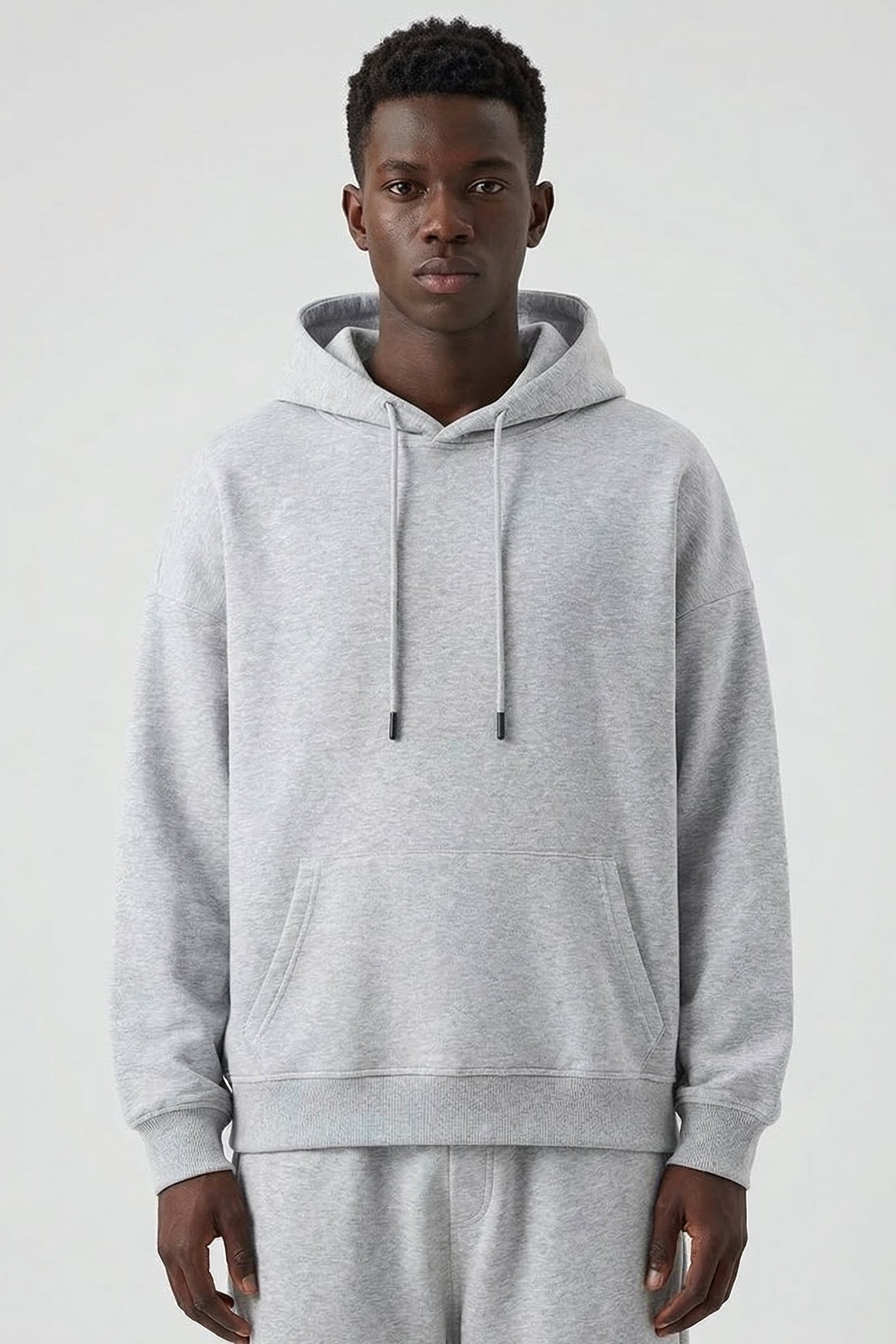 Man wearing a gray hoodie and pants on a white background