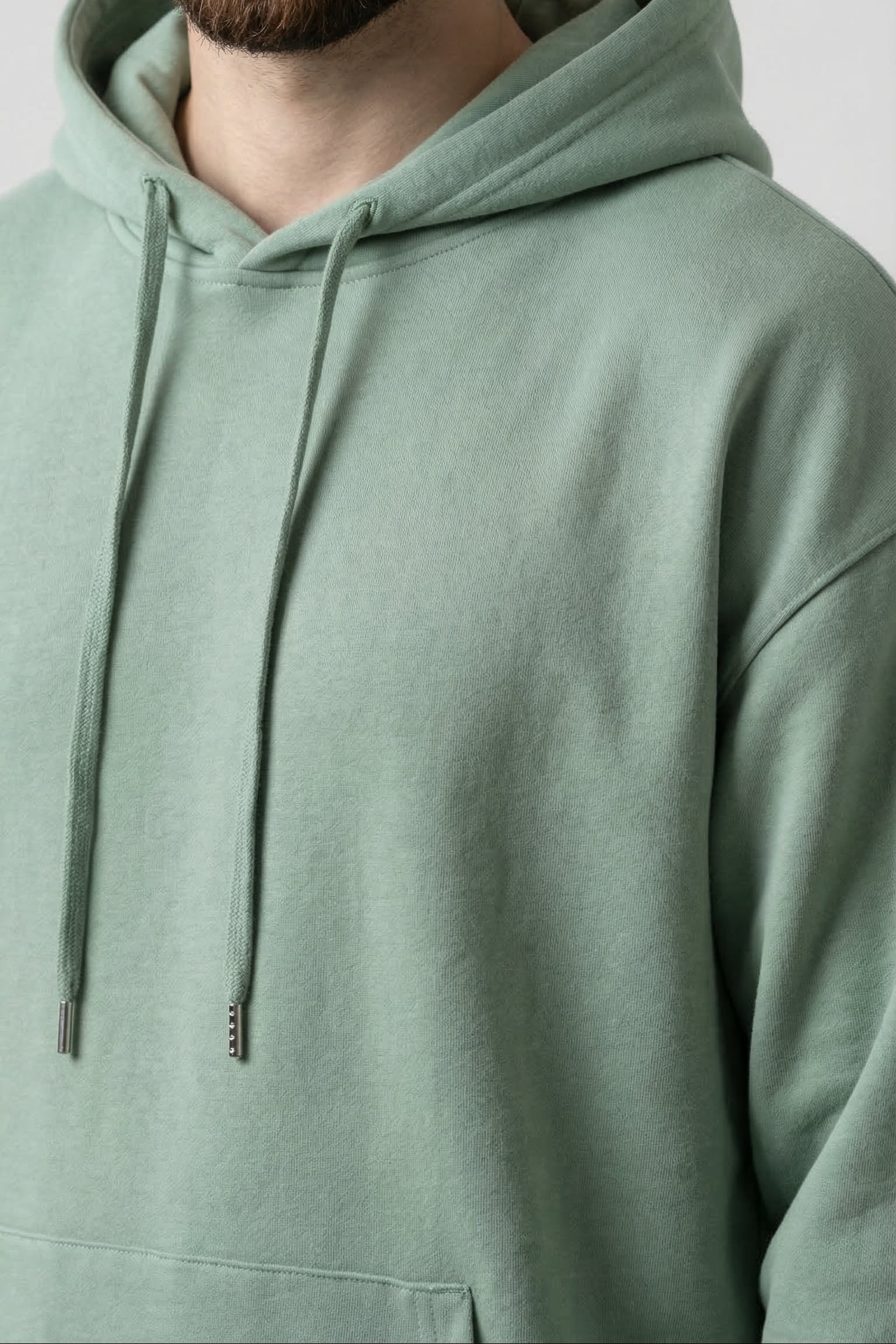 Person wearing a light green hoodie against a plain background