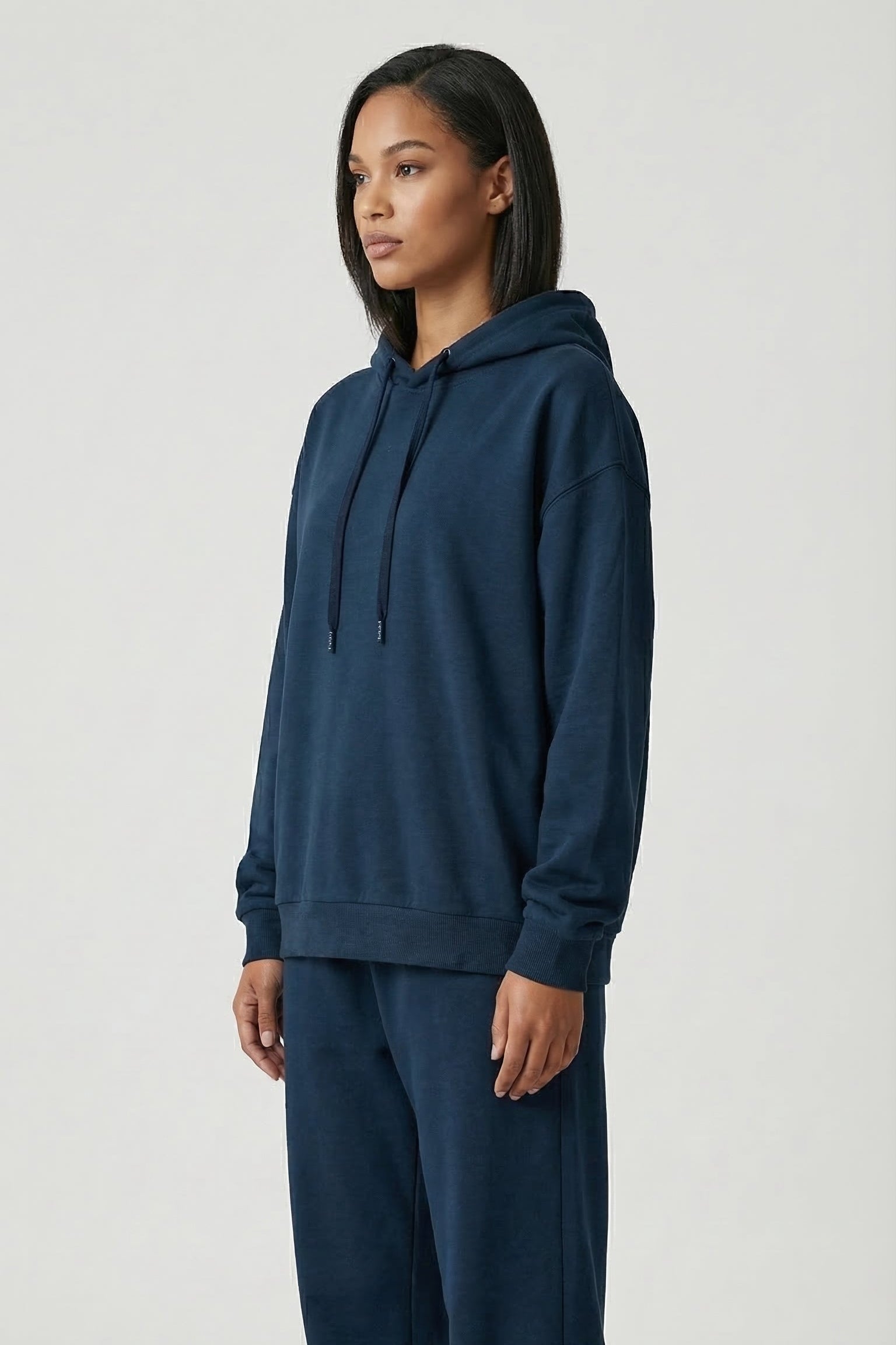 Person wearing a navy blue hoodie and pants on a white background