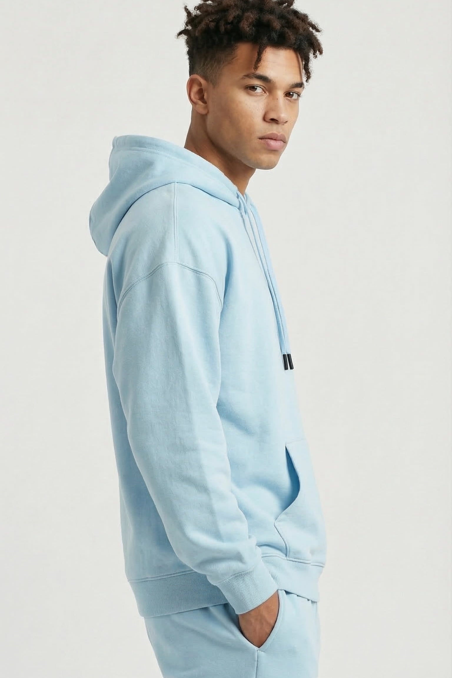 Person wearing a light blue hoodie and pants on a plain background