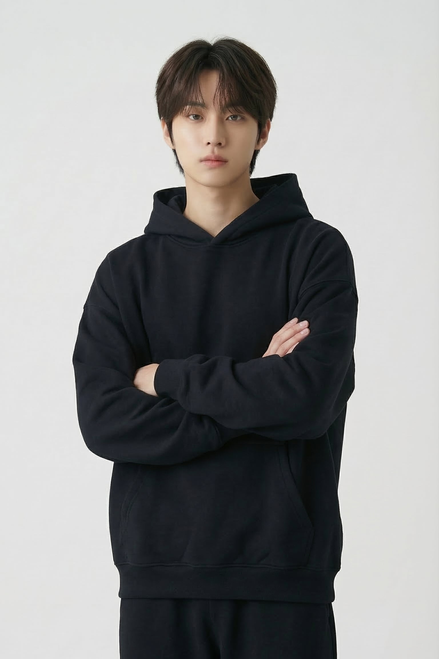 Person wearing a black hoodie and pants on a white background