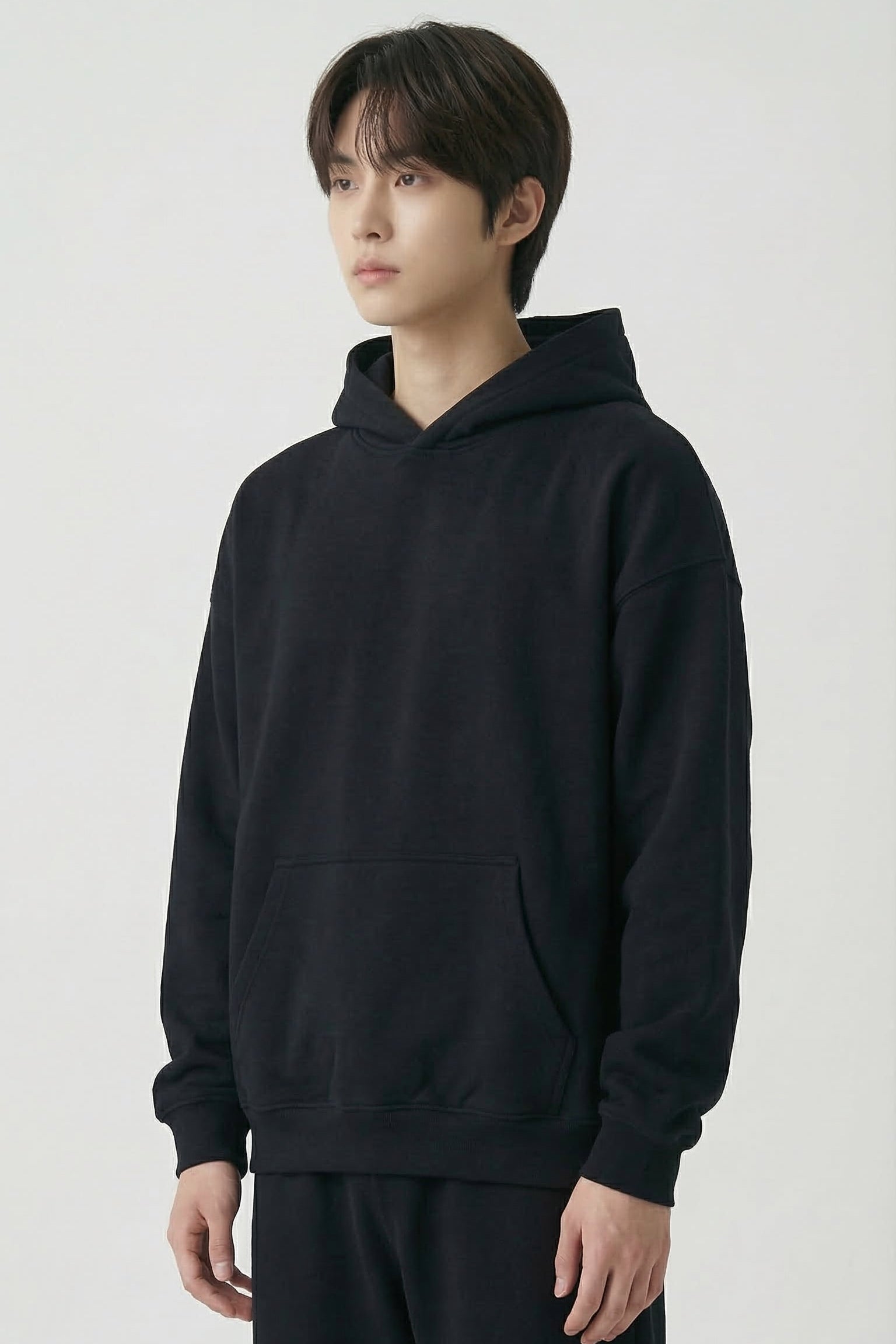 Person wearing a black hoodie and pants on a white background