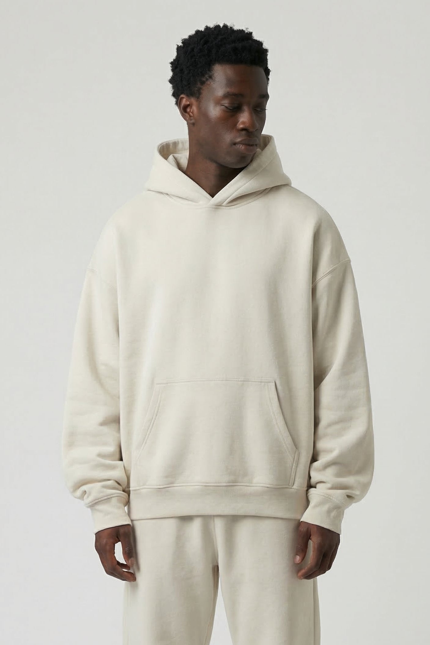 Man wearing a beige hoodie and pants set on a white background