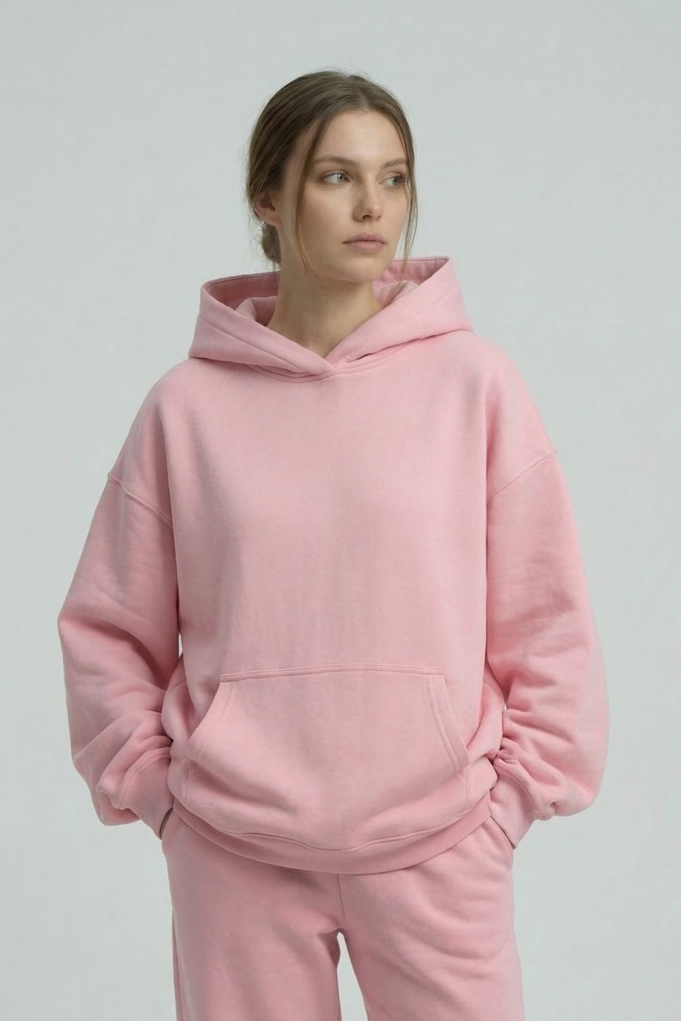 Person wearing a pink hoodie and pants on a plain background