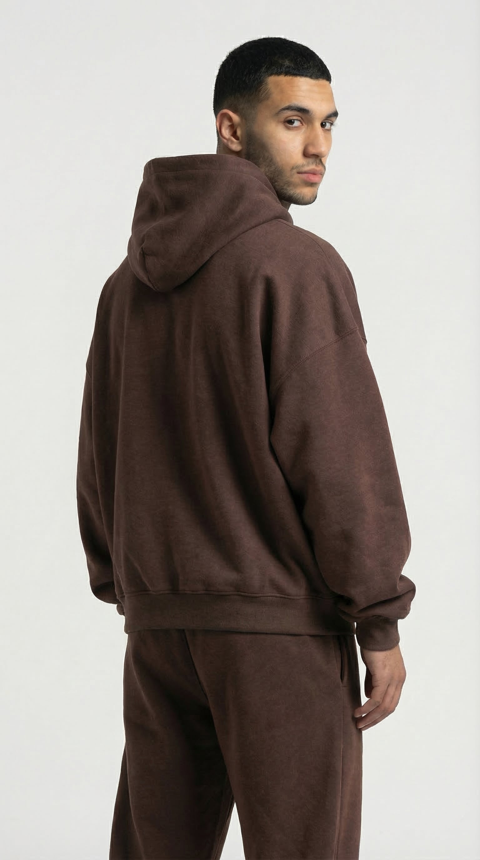 Man wearing a brown hoodie and pants on a white background