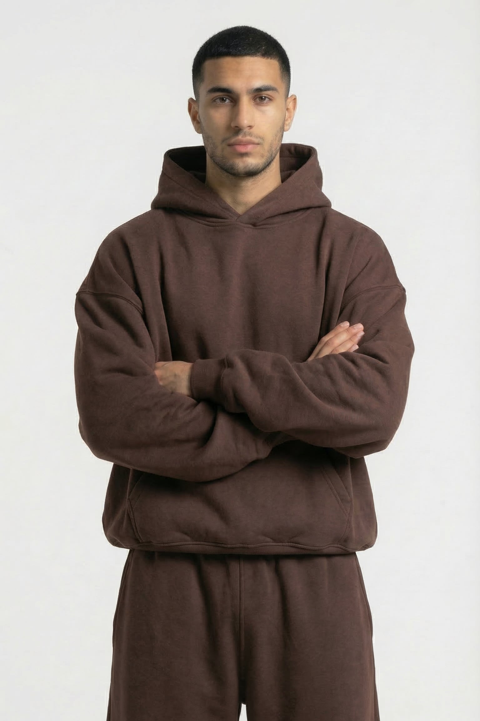 Man wearing a brown hoodie and pants on a white background