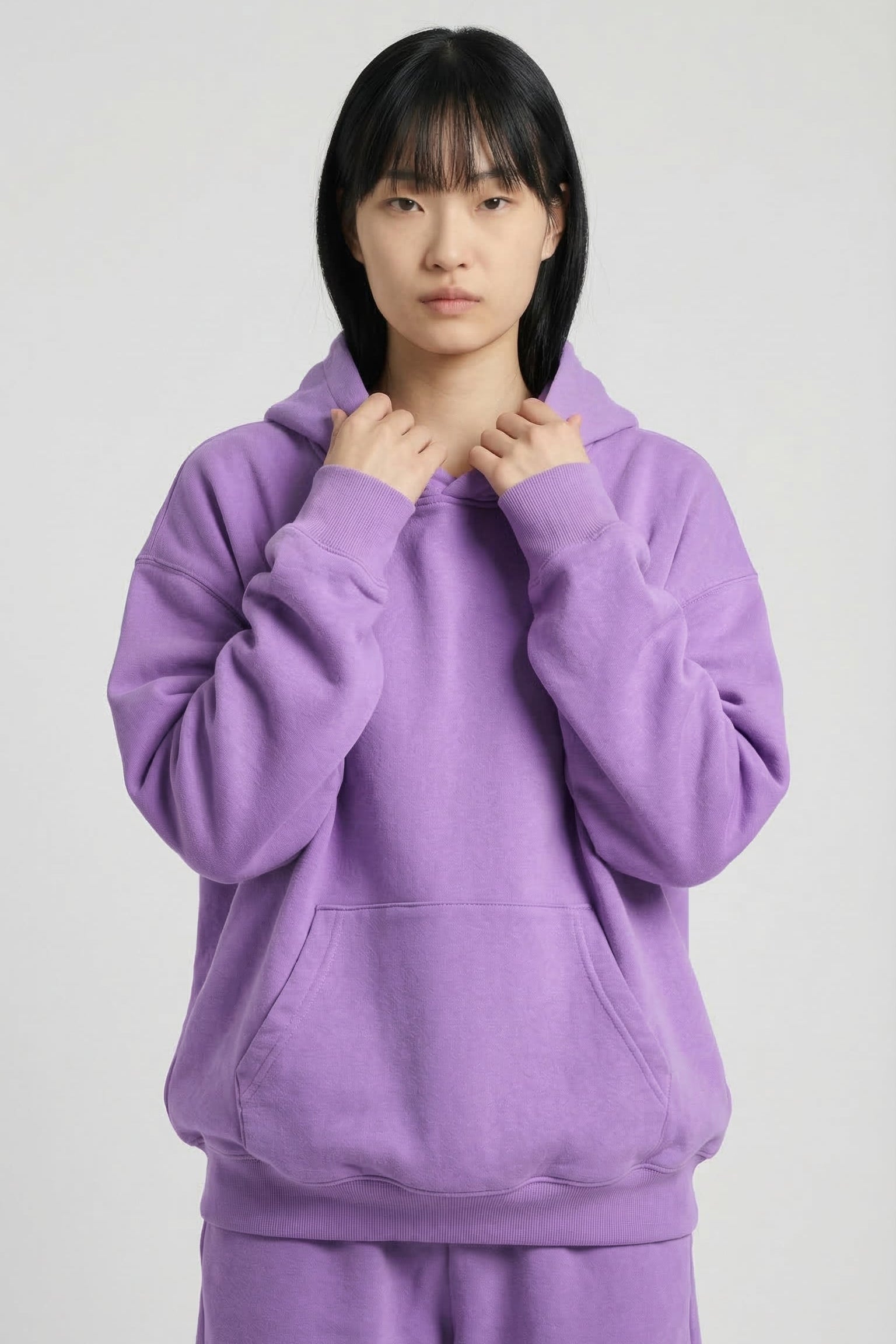 Person wearing a purple hoodie and pants on a white background