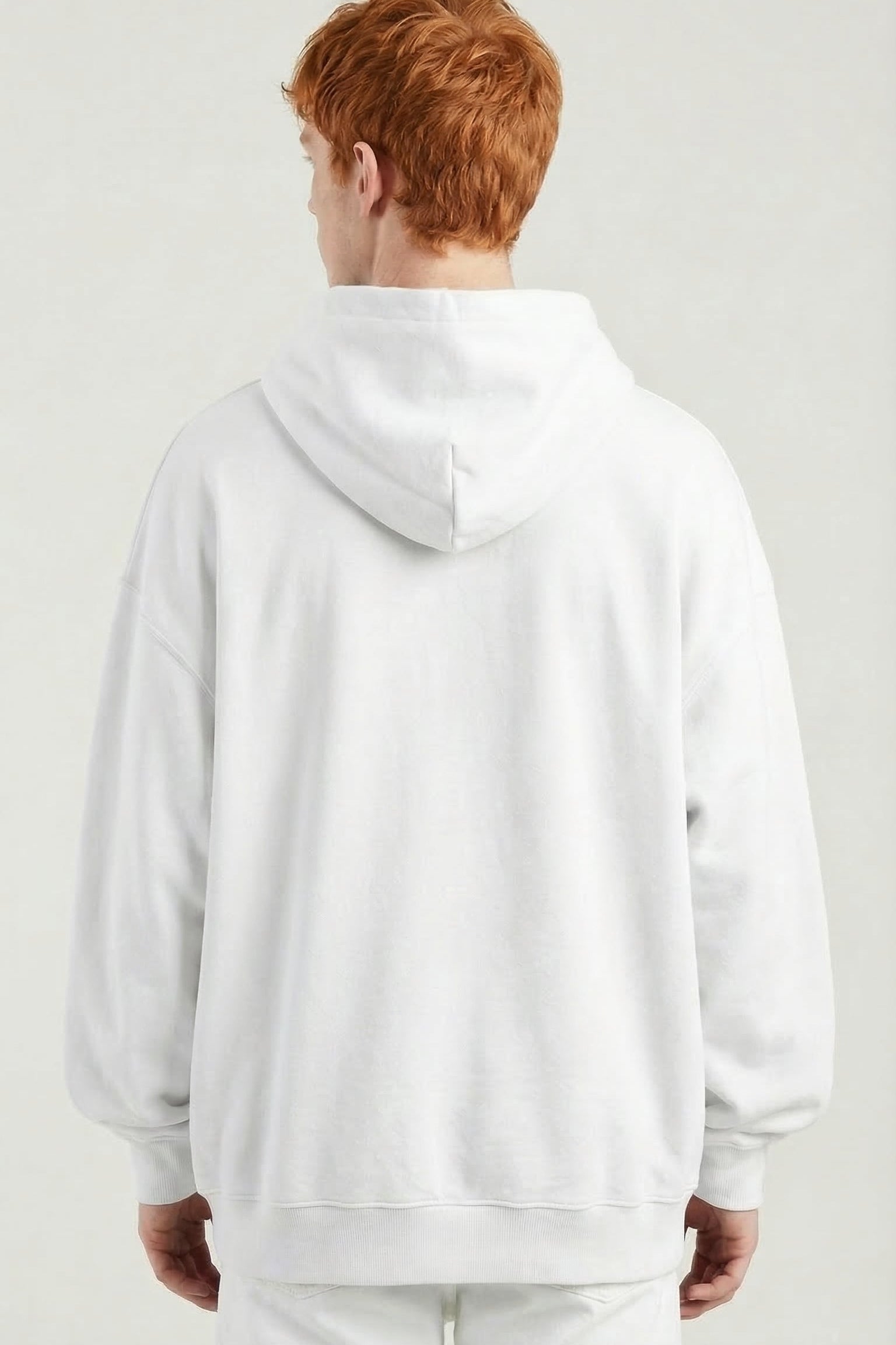 Person wearing a white hoodie and pants on a plain background