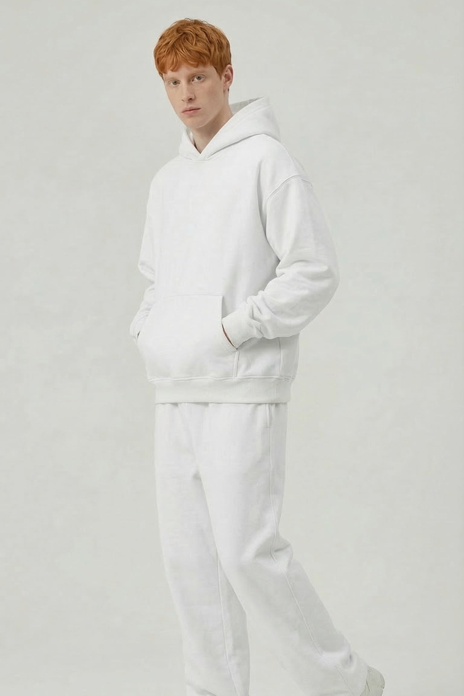 Person wearing a white hoodie and pants on a light gray background