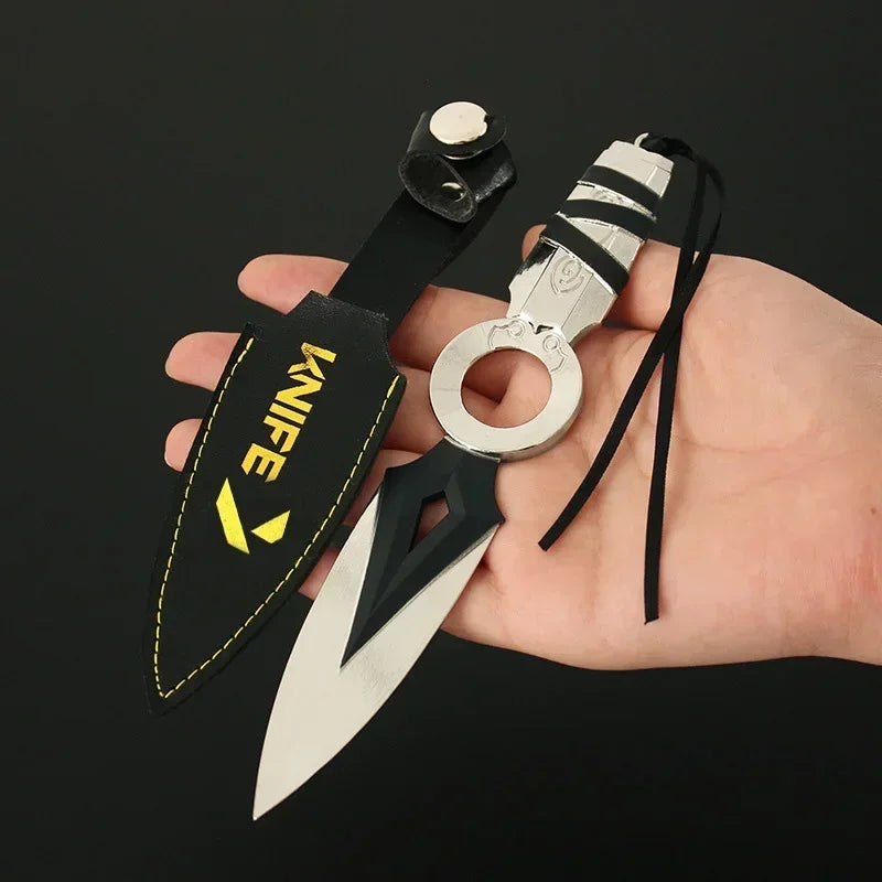 Kunai knife keychain in hand with black sheath, yellow “KNIFE” logo, and silver ring