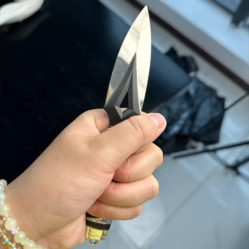 Kunai knife keychain held outdoors, white double-blade with geometric black insert