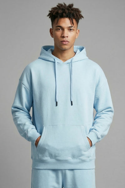 Person wearing a light blue hoodie and pants on a gray background