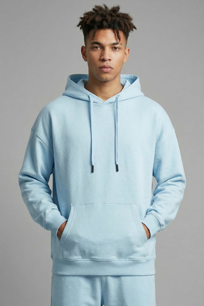 Person wearing a light blue hoodie and pants on a gray background