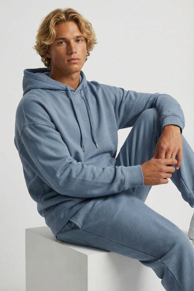 Person wearing a blue tracksuit sitting on a white block against a light gray background