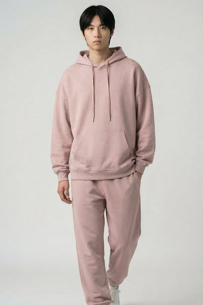 Person wearing a pink hoodie and pants set on a white background