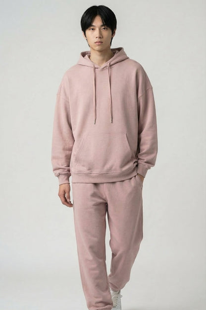 Person wearing a pink hoodie and pants set on a white background