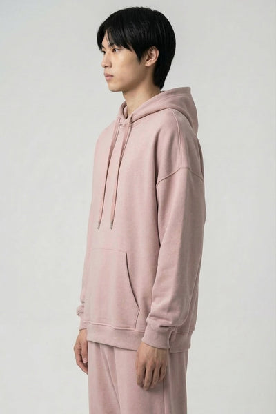 Person wearing a pink hoodie and pants on a white background