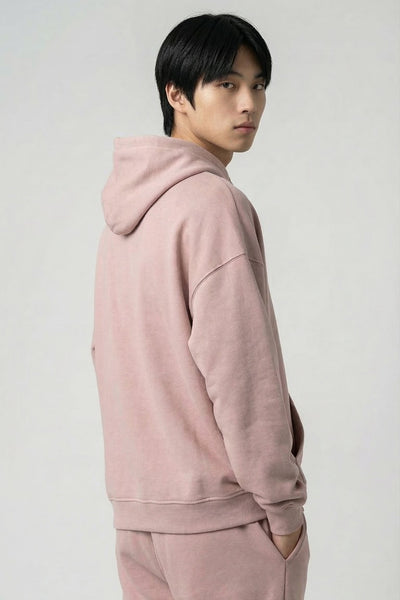Person wearing a pink hoodie and pants on a white background