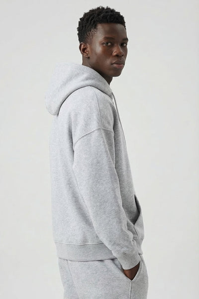 Person wearing a gray hoodie and pants on a white background