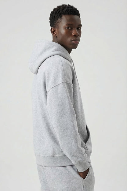 Person wearing a gray hoodie and pants on a white background
