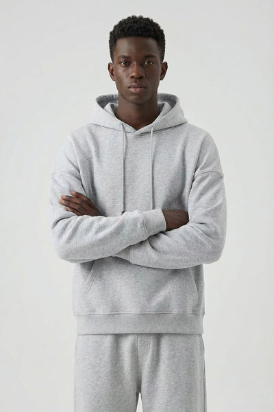 Person wearing a gray hoodie and pants on a white background