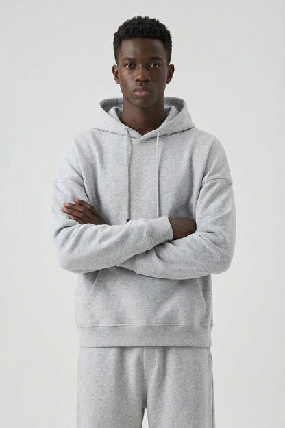 Person wearing a gray hoodie and pants on a white background