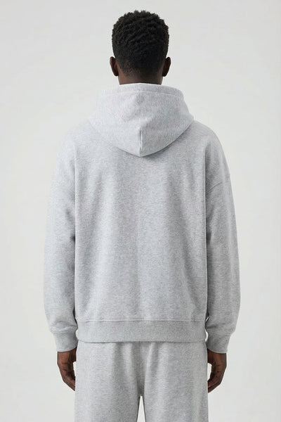 Person wearing a gray hoodie and pants on a white background