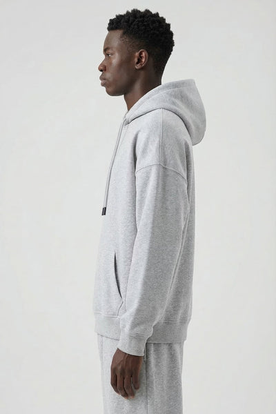 Person wearing a gray hoodie and pants on a white background