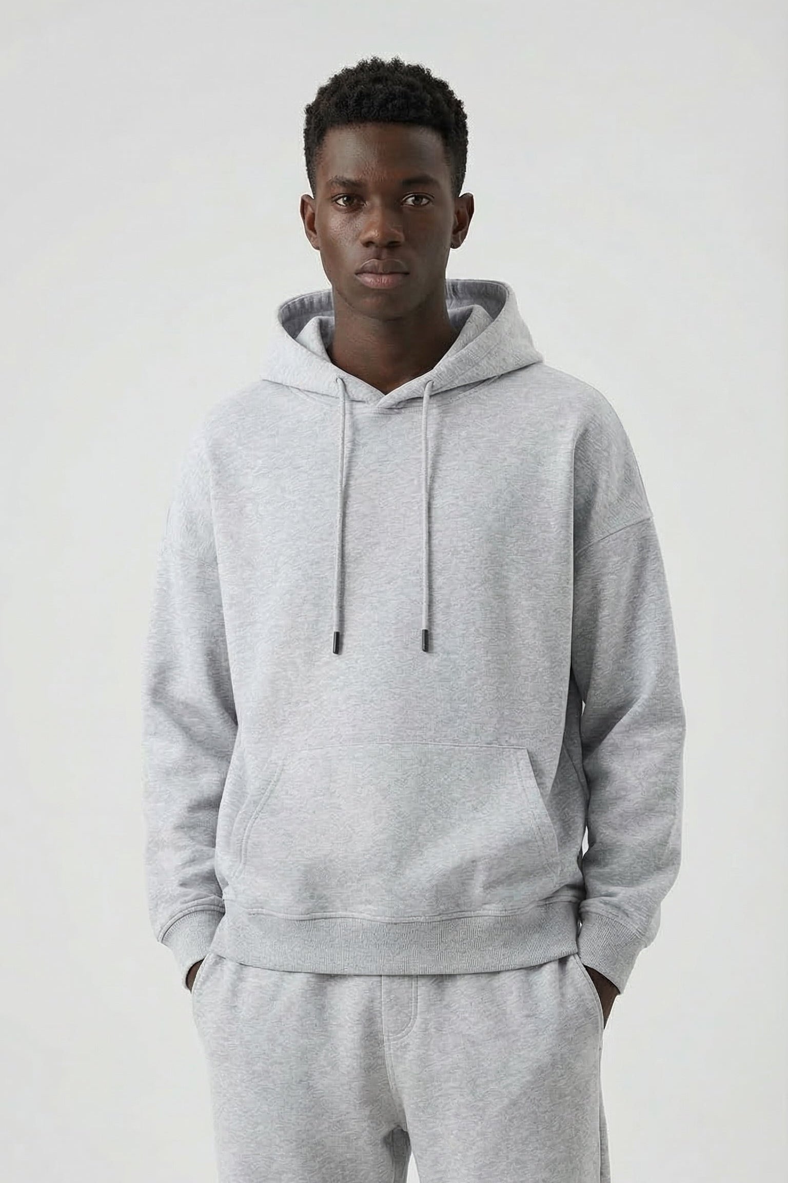 Person wearing a gray hoodie and pants on a white background