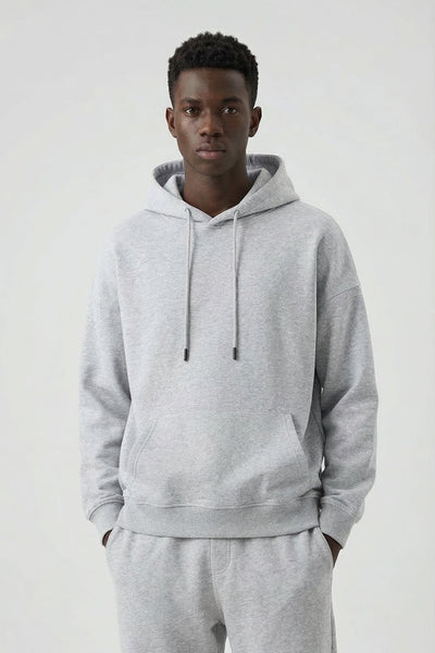 Person wearing a gray hoodie and pants on a white background