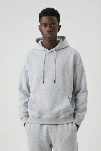 Person wearing a gray hoodie and pants on a white background