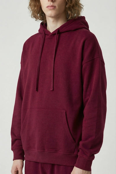 Person wearing a maroon hoodie and pants on a white background