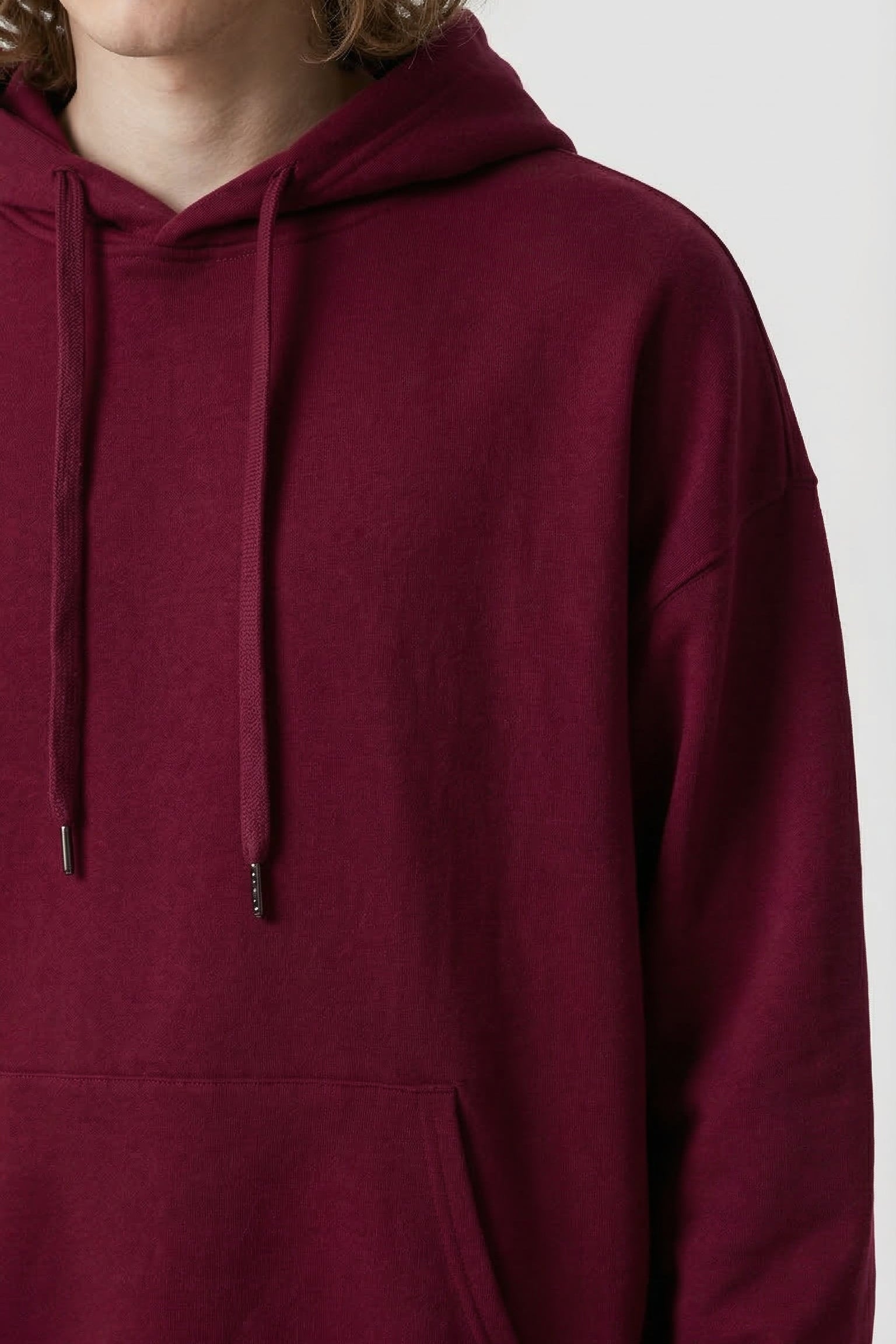 Maroon hoodie worn by a person on a white background