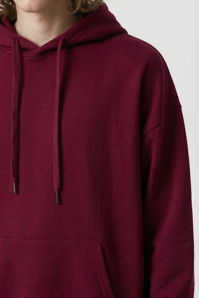 Maroon hoodie worn by a person on a white background
