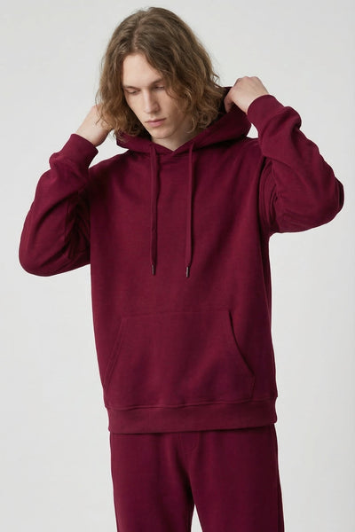 Person wearing a maroon hoodie and pants on a white background