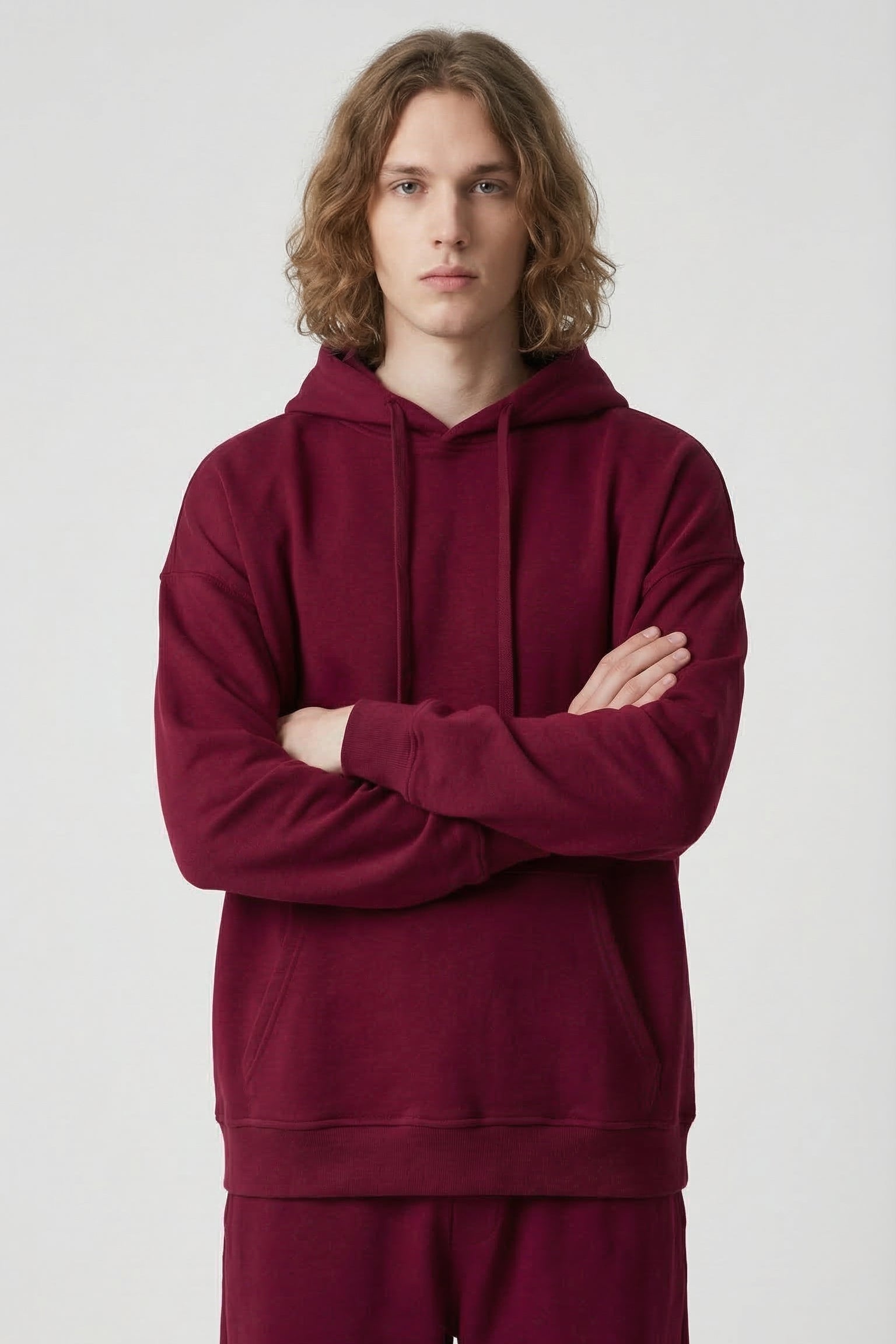 Person wearing a burgundy hoodie and pants on a white background
