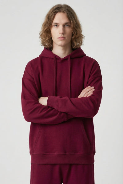 Person wearing a burgundy hoodie and pants on a white background