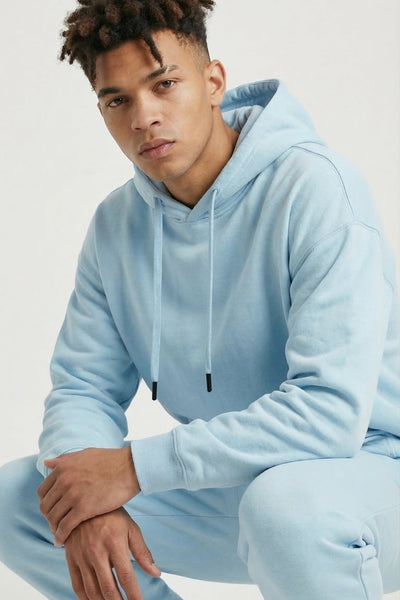 Person wearing a light blue hoodie and pants on a white background