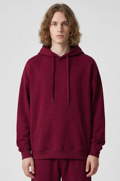 Person wearing a maroon hoodie and pants on a white background