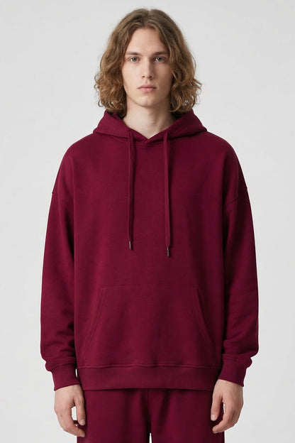 Person wearing a maroon hoodie and pants on a white background