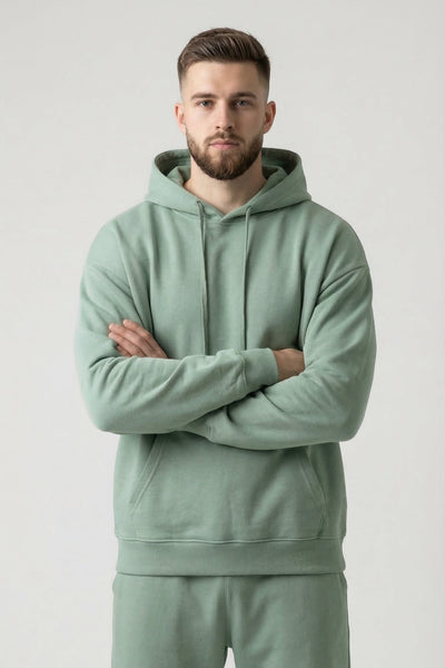 Man wearing a light green hoodie and pants on a plain background