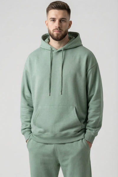 Man wearing a light green hoodie and pants on a plain background