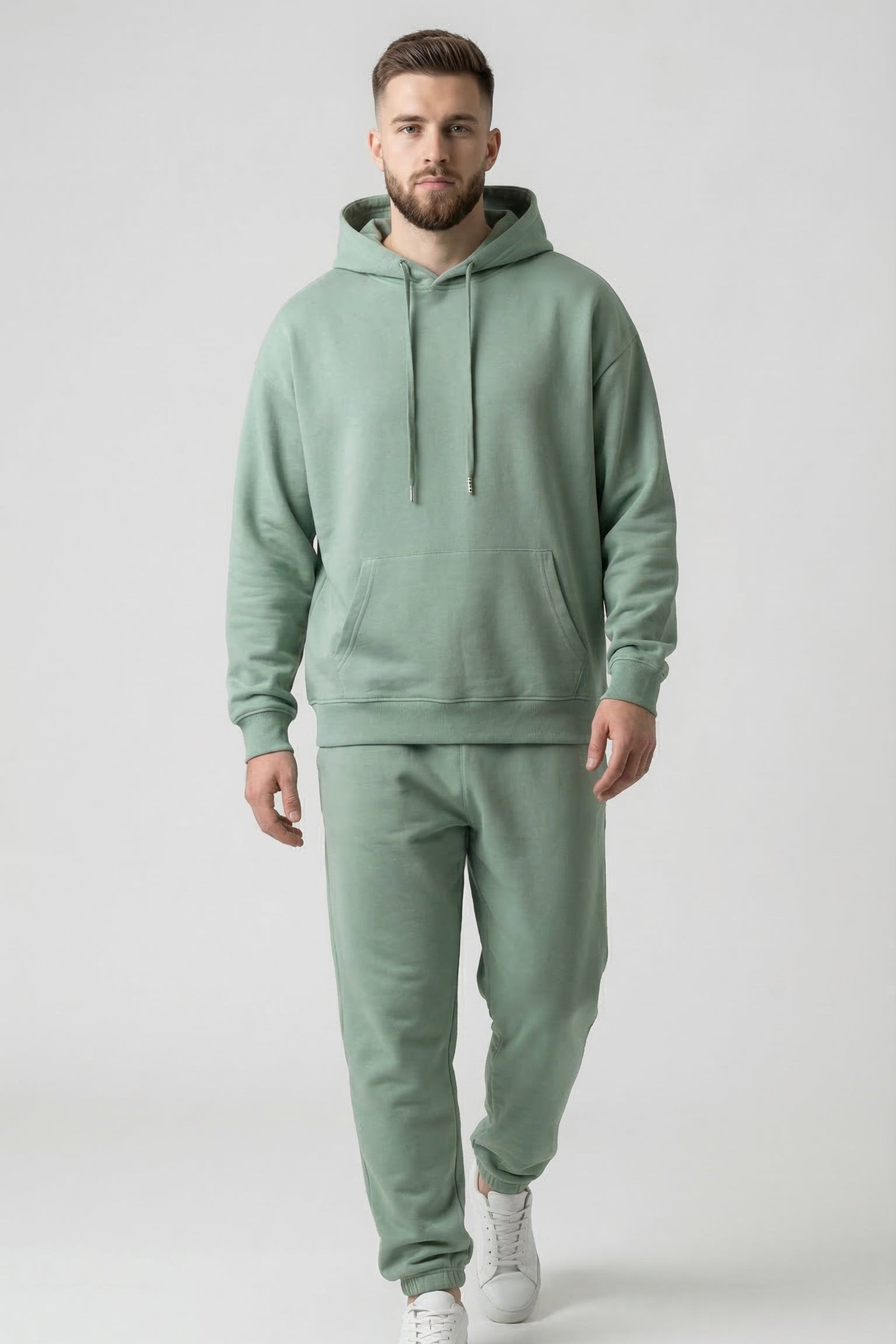 Man wearing a green hoodie and jogger set on a white background