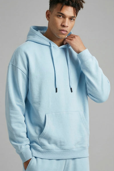 Person wearing a light blue hoodie and pants against a gray background