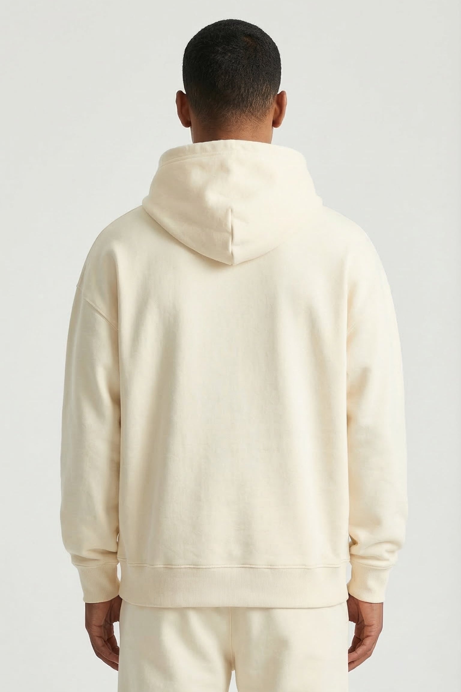 Person wearing a cream-colored hoodie and pants on a light gray background