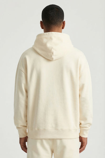 Person wearing a cream-colored hoodie and pants on a light gray background