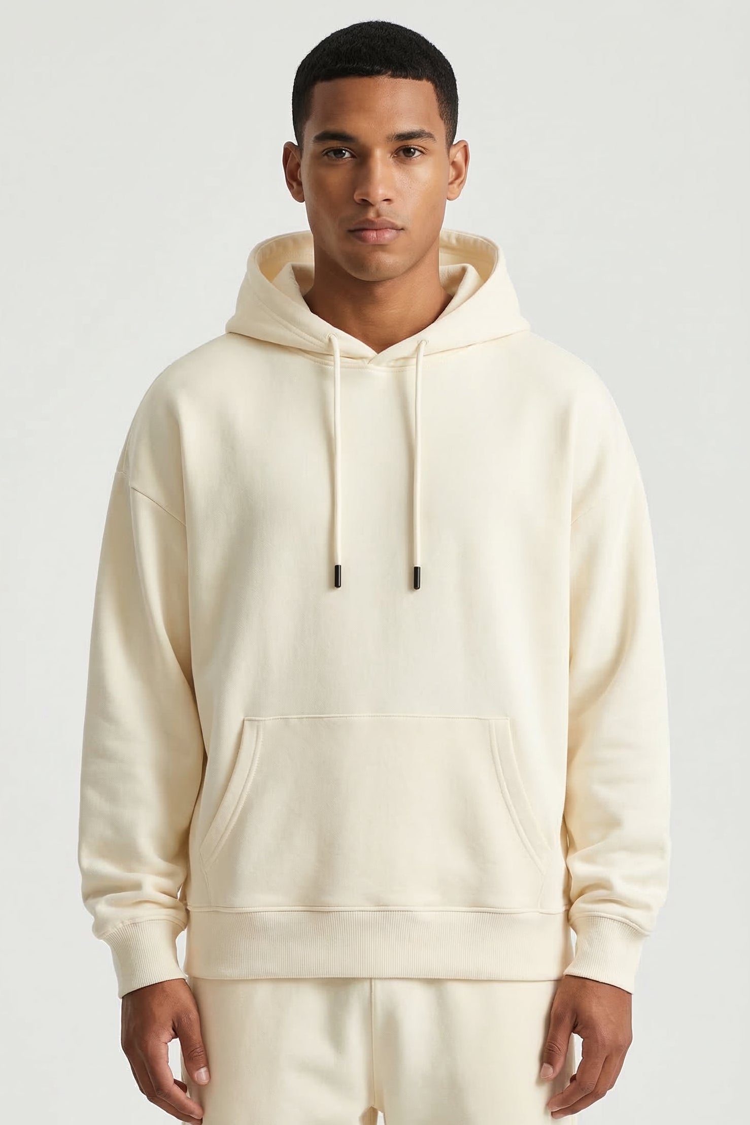 Man wearing a cream hoodie and pants on a white background