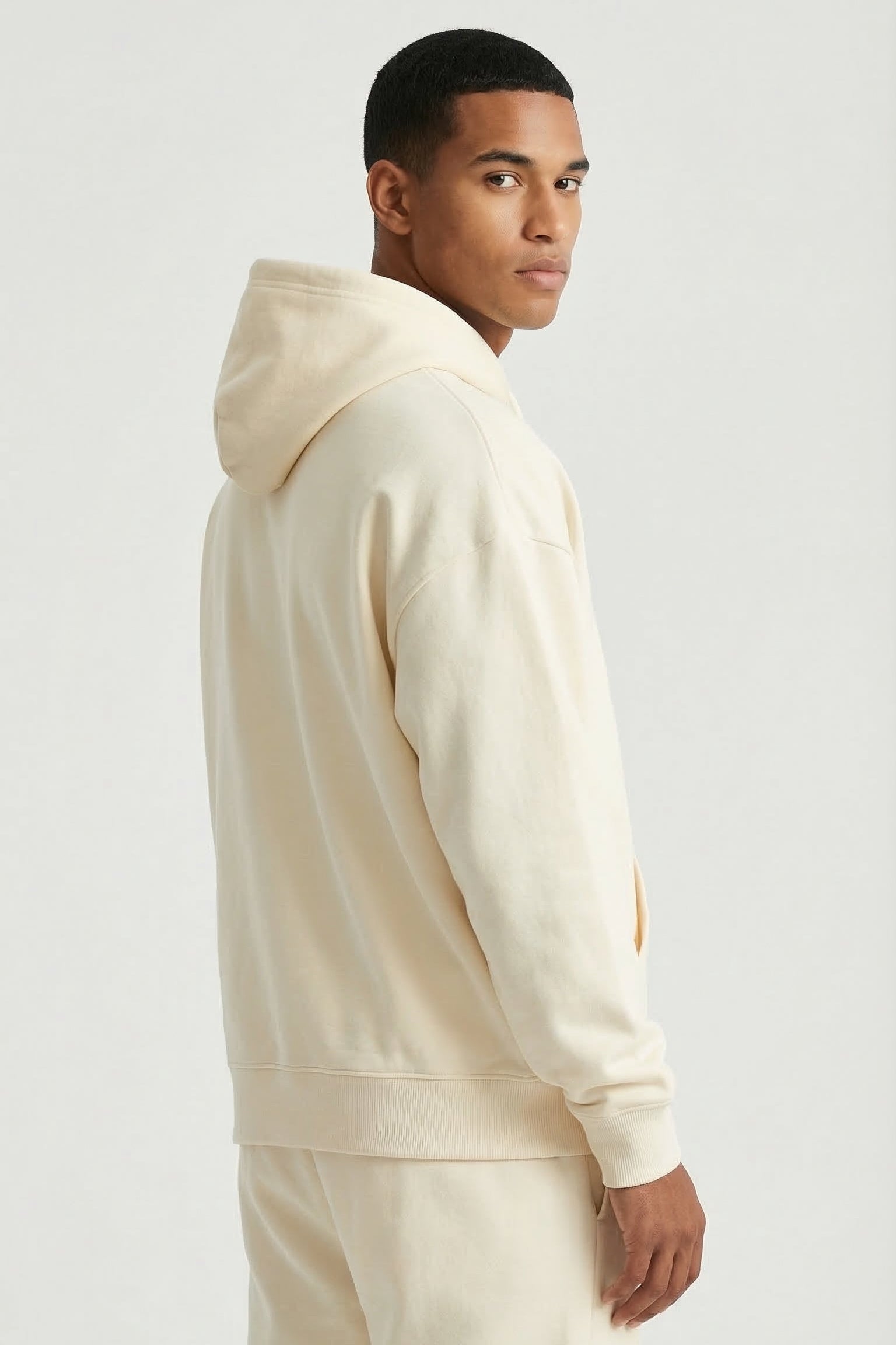 Man wearing a beige hoodie and pants on a white background